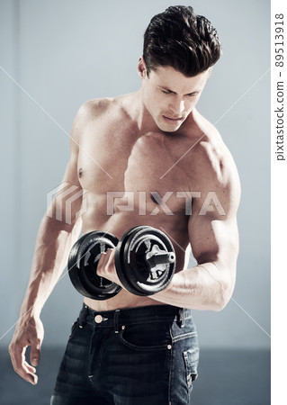 Fully focused on keeping fit. A masculine male with no shirt on lifting weights. Fully focused on keeping fit. A masculine male with no shirt on lifting weights. 89513918