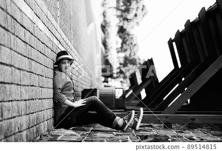 Turning the place upside down. A woman appears to be sitting on the side of a building with her back against the sidewalk - perspective. Turning the place upside down. A woman appears to be sitting on the side of a building with her back against the sidewalk - perspective. 89514815