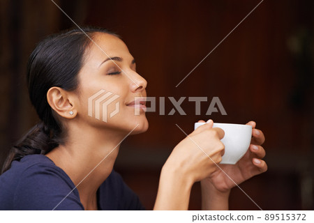 The delicious aroma of freshly ground coffee. A young woman drinking a cup of coffee outside. 89515372