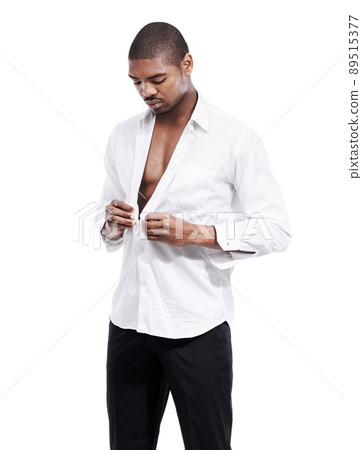Buttoning up. A handsome young man buttoning his shirt open in the studio. 89515377
