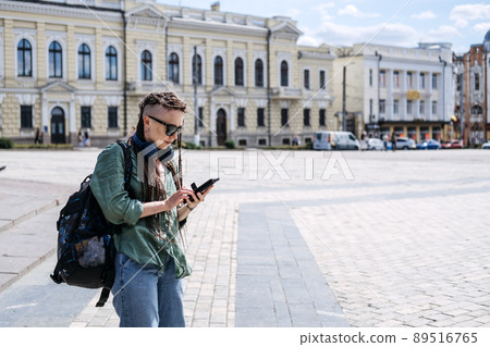 City Summer Vacation, urban trip. Exploring new places, cities around world. City travel outfit. Hipster woman traveler with dreadlocks headphones and cell phone on summer city background 89516765