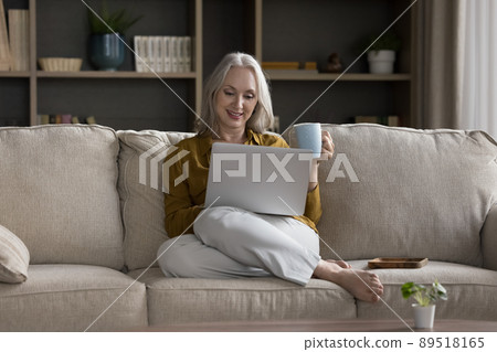 Happy retired grey haired homeowner woman watching online movie Happy retired grey haired homeowner woman watching online movie 89518165