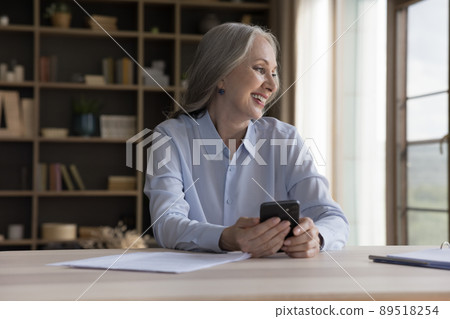Happy senior grey haired cellphone user woman holding mobile phone 89518254