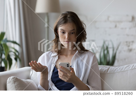Shocked cellphone user girl staring at screen, looking at smartphone Shocked cellphone user girl staring at screen, looking at smartphone 89518260