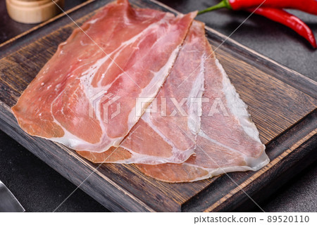Italian prosciutto crudo or spanish jamon on a dark cutting board Italian prosciutto crudo or spanish jamon on a dark cutting board 89520110