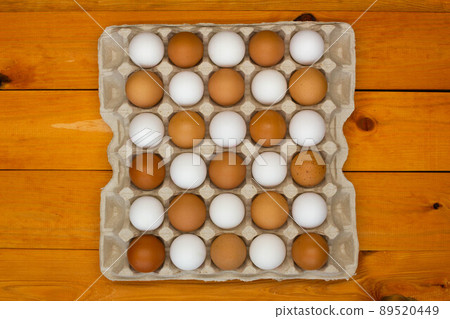 Chicken eggs in a package on the table. Brown and white chicken eggs in the egg tray in a checkerboard pattern. Natural eco-friendly products. Fresh chicken raw eggs in the chequerwise. Close-up Chicken eggs in a package on the table. Brown and white chicken eggs in the egg tray in a checkerboard pattern. Natural eco-friendly products. Fresh chicken raw eggs in the chequerwise. Close-up 89520449
