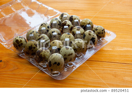 Quail eggs in a package on the table. Spotted quail eggs in a transparent box on a wooden background. Natural eco-friendly healthy products. Lots of fresh quail raw eggs in the egg tray. Close-up Quail eggs in a package on the table. Spotted quail eggs in a transparent box on a wooden background. Natural eco-friendly healthy products. Lots of fresh quail raw eggs in the egg tray. Close-up 89520451