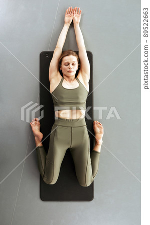 Above view of calm young woman with closed eyes lying in hero pose while doing exercise for knees 89522663