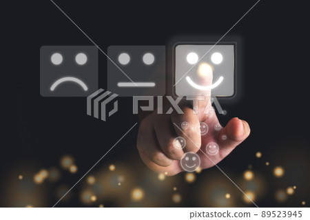 Evaluation and satisfaction concept. Index Finger of hand points to smile emotion that shows an excellent job. Close up shot with gold bokeh glitter on black background. 89523945