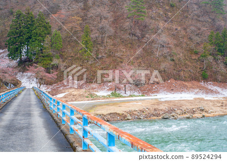 View from the snow-melted Uono River Shinbenbashi, a tributary of the Chikuma River, near the Yuzawa IC on the Kan-Etsu Expressway, remaining snow, early spring scenery 89524294