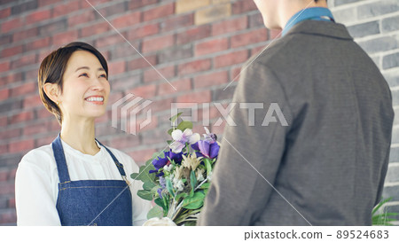 A female florist clerk handing a bouquet Flower arrangement A female florist clerk handing a bouquet Flower arrangement 89524683