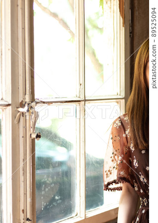 Image of a young woman standing by the window of a Western-style building Image of a young woman standing by the window of a Western-style building 89525094