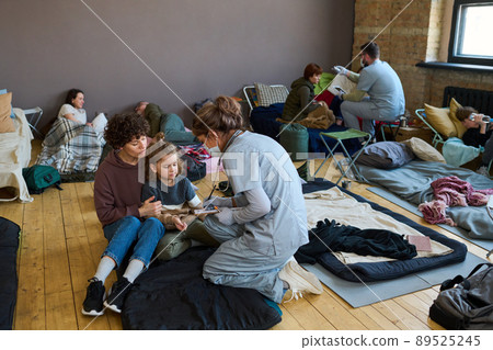 Healthcare worker giving medical help to young female refugee and little boy 89525245