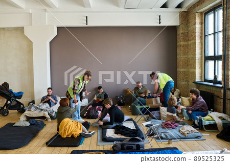 Two young volunteers spreading humanitarian help between refugees 89525325