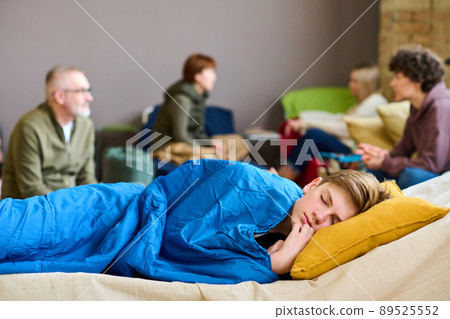 Cute serene boy with his head on pillow sleeping under blanket on couchette Cute serene boy with his head on pillow sleeping under blanket on couchette 89525552