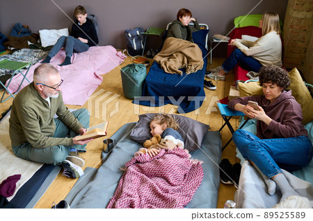 Senior man with open book of fairy tales sitting in front of sleeping grandson 89525589