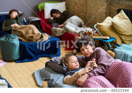 Cute boy with smartphone and his mother looking at screen while resting in bed Cute boy with smartphone and his mother looking at screen while resting in bed 89525594