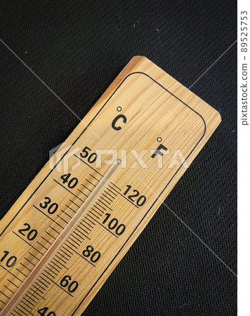 Analogue wooden thermometer with red measuring liquid on black background 89525753