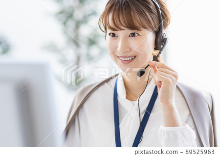 A business woman talking on the phone with a headset in front of a computer A business woman talking on the phone with a headset in front of a computer 89525963