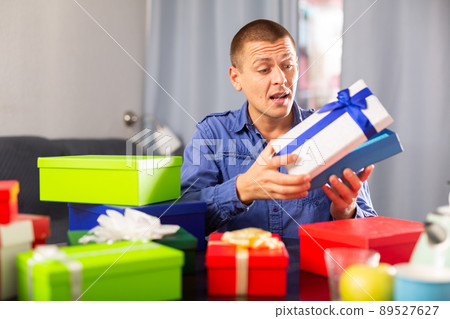 Man sitting with many presents in colorful boxes Man sitting with many presents in colorful boxes 89527627