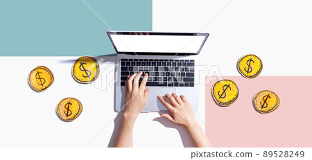 Person using a laptop computer with coins - earn online theme Person using a laptop computer with coins - earn online theme 89528249