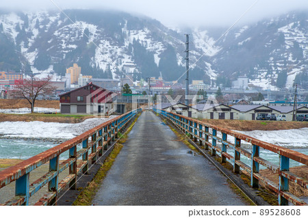 View from the snow-melted Uono River Shinbenbashi, towards Yuzawa Station, near the Yuzawa IC on the Kanetsu Expressway, remaining snow, early spring scenery 89528608