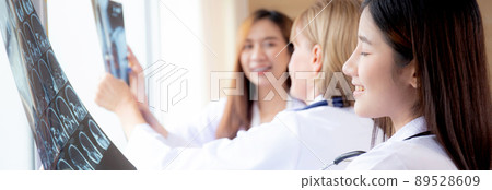 Group of team doctors examining x-ray film about skull and skeleton of patient for checking disease. 89528609