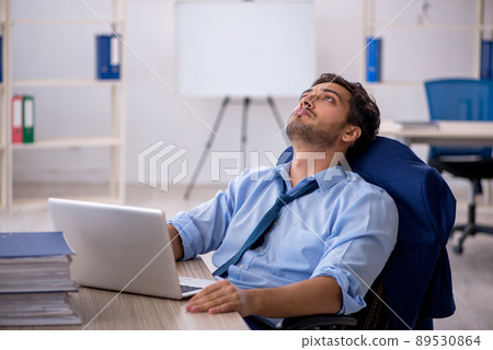 Young businessman employee and too much work in the office Young businessman employee and too much work in the office 89530864