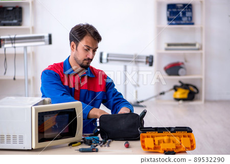 Young male repairman repairing oven at workshop Young male repairman repairing oven at workshop 89532290