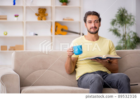 Young man reading book at home during pandemic 89532316