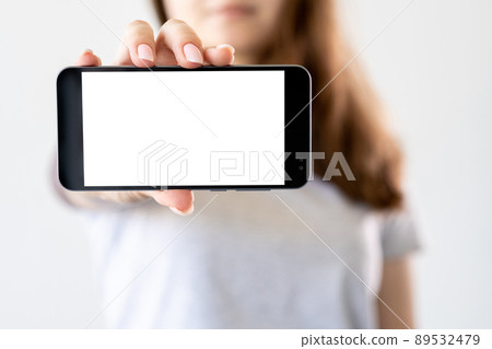 Mobile entertainment. Digital advertising. Online connection. Unrecognizable woman holding smartphone with blank screen isolated white. Mobile entertainment. Digital advertising. Online connection. Unrecognizable woman holding smartphone with blank screen isolated white. 89532479