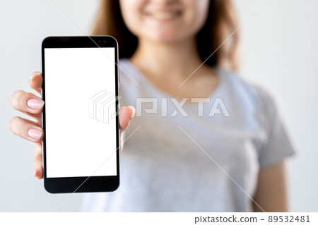 Mobile mockup. Digital technology. Online connection. Unrecognizable woman holding in hands smartphone with blank screen isolated white. Mobile mockup. Digital technology. Online connection. Unrecognizable woman holding in hands smartphone with blank screen isolated white. 89532481