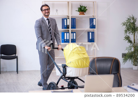 Young male employee looking after new born at workplace 89534200