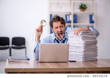 Young male employee and too much work in the office 89534224