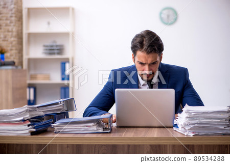 Young male employee and too much work in the office 89534288
