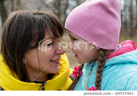 Portrait of a mother and her daughter face-to-face. A five-year-old Ukrainian girl laughing with her mother. Family, relationships concept. Portrait of a mother and her daughter face-to-face. A five-year-old Ukrainian girl laughing with her mother. Family, relationships concept. 89535401