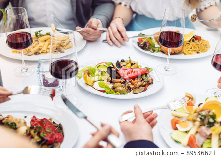 Four friends eating Italian food in fancy restaurant, close-up 89536621
