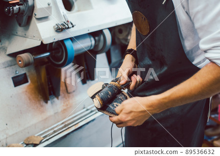 Close-up of cobbler working on pair of shoes with machine 89536632