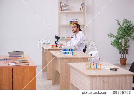 Young male chemist sitting at the desk in the classroom Young male chemist sitting at the desk in the classroom 89536768