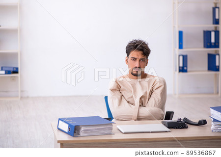 Crazy young man in straitjacket at the office 89536867