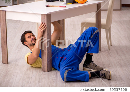 Young male carpenter repairing table at home 89537506