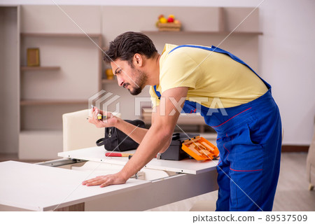 Young male carpenter repairing table at home Young male carpenter repairing table at home 89537509