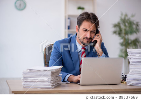 Young male employee and too much work in the office Young male employee and too much work in the office 89537669
