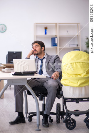 Young male employee looking after new born at workplace 89538208