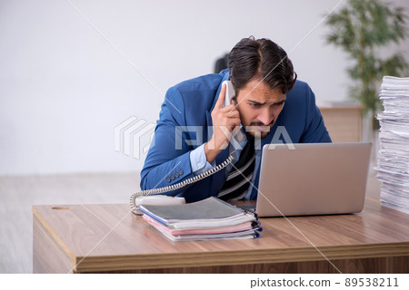 Young male employee unhappy with excessive work in the office 89538211