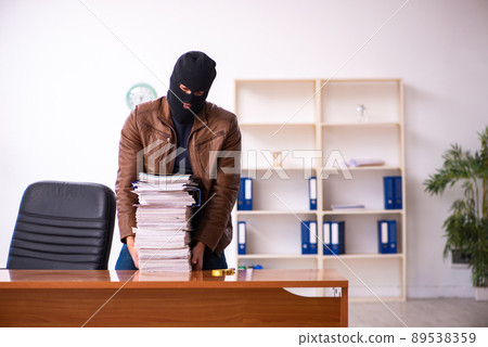 Young man in balaclava stealing information from the office 89538359