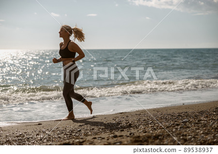 Sporty young female enjoying jogging along beautiful coast 89538937