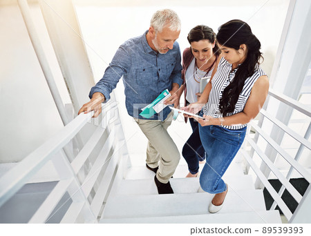 Working on the go. High angle shot of three colleagues looking at a digital tablet. 89539393
