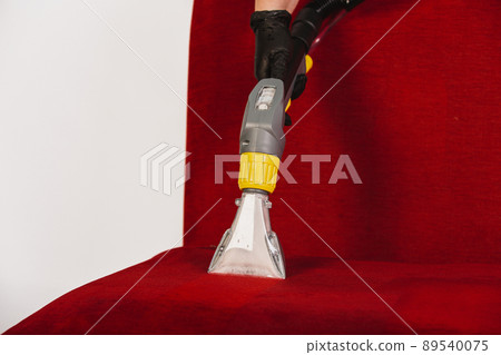hand in black glove cleans red sofa with electrical appliances hand in black glove cleans red sofa with electrical appliances 89540075