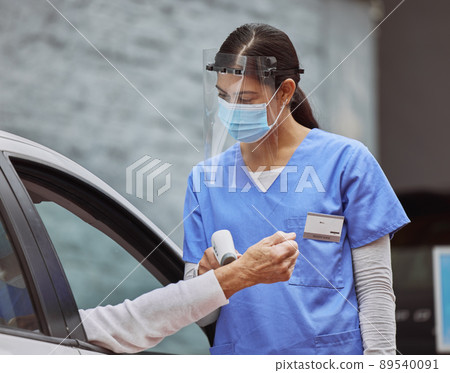 Your temperature seems normal. Shot of a young healthcare worker taking a patient's temperature at a drive through vaccination site. 89540091